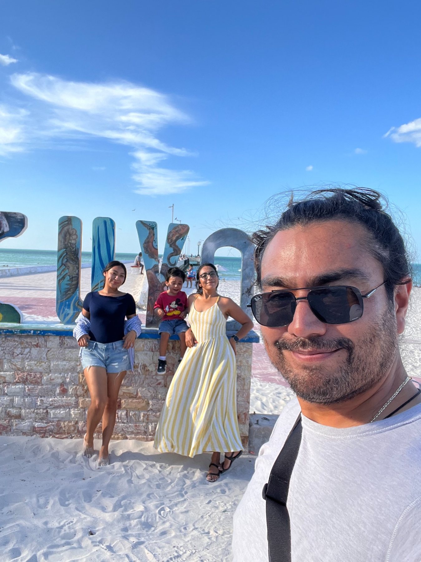 Family travel photo at the El Cuyo beach sign in Yucatán