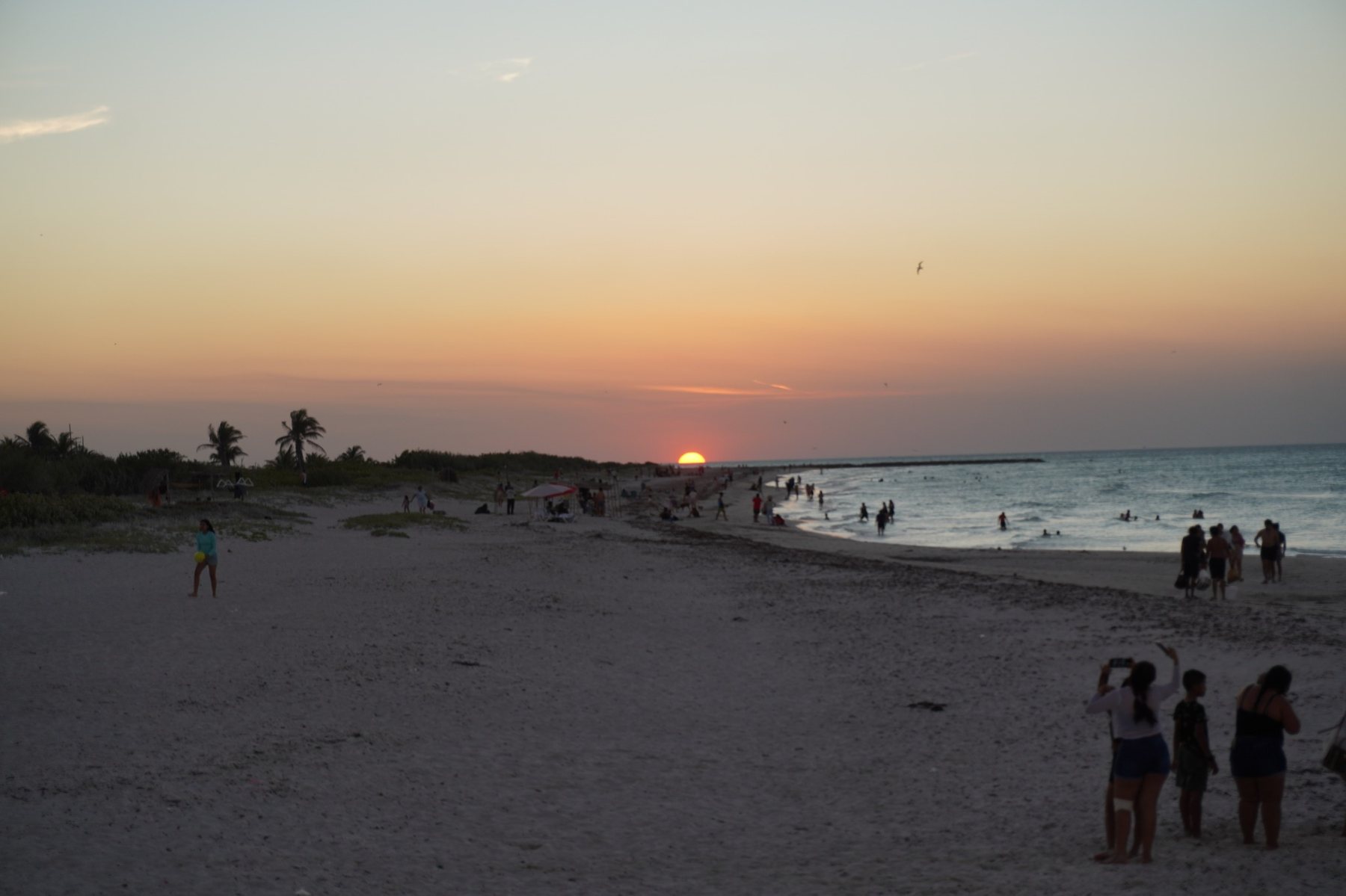 Wide view of El Cuyo beach at sunset with calm water and people enjoying the shore