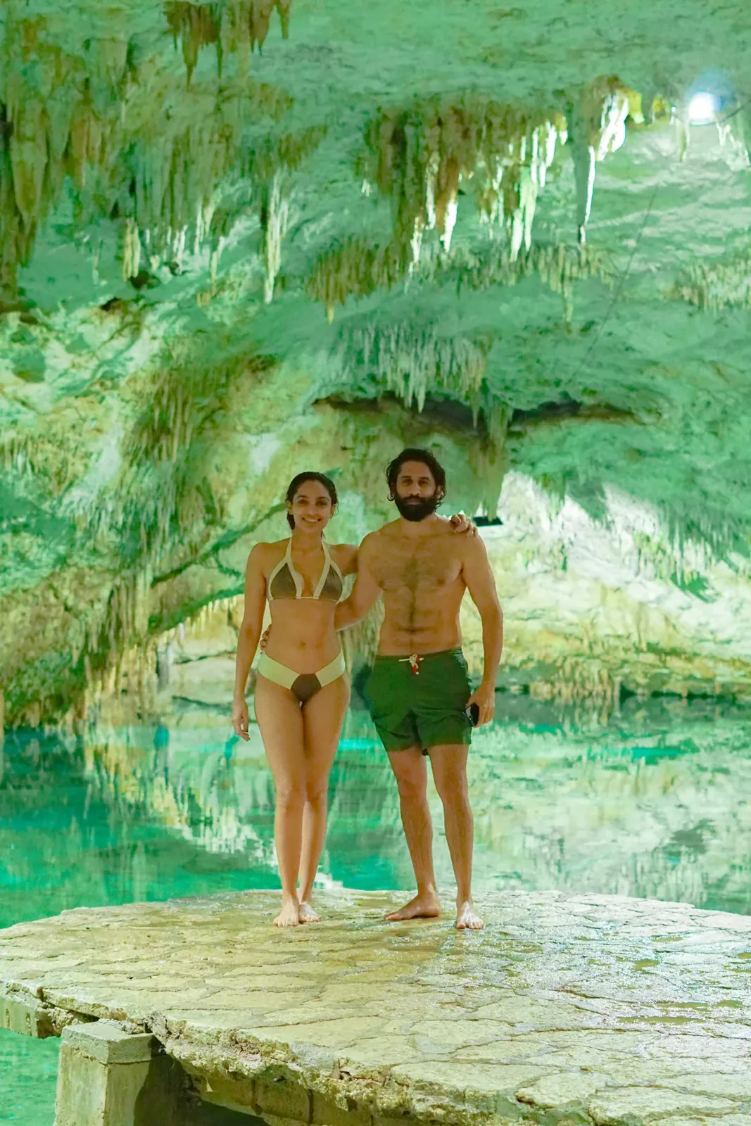 Guests beside the turquoise water and stalactites inside Cenote Taak Bi Ha